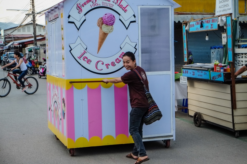 A street vendor moving her ice cream stand through town, getting ready for the night market.